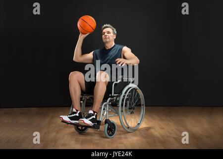 Deaktiviert Basketball Player auf Rollstuhl wirft Ball Stockfoto