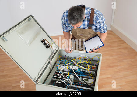 Elektriker am Sicherungskasten Holding Zwischenablage suchen Stockfoto