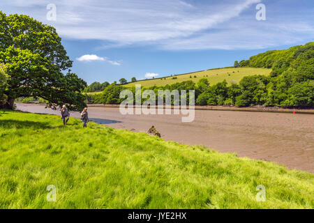 Zwei Damen, die entlang einer ruhigen und bewaldeten Strecke des Flusses Dart bei Ebbe in der Nähe von Sharpham, Devon, England, Großbritannien Stockfoto