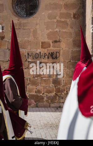 Detail Pönitenten rot hält eine Kerze in der Karwoche, Graffiti an der Wand name Mohamed, in Linares, Provinz Jaén, Spanien Stockfoto