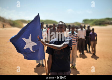 Ein junger Mann trägt die somalische Fahne während der Führung einer Gruppe von Soldaten, die während einer Demonstration durch einen lokalen Milizen, gebildet, um die Sicherheit in der Nähe von Marka, Somalia, am 30. April. AU UN (14077872251) Stockfoto