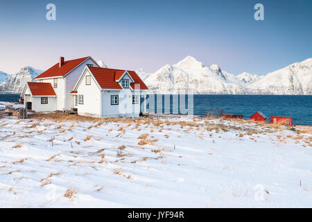 Blauer Himmel über die Holzhütten genannt Rorbu eingerahmt von gefrorenen Meer und schneebedeckten Gipfeln Djupvik Lyngen Alpen Tromsø Norwegen Europa Stockfoto