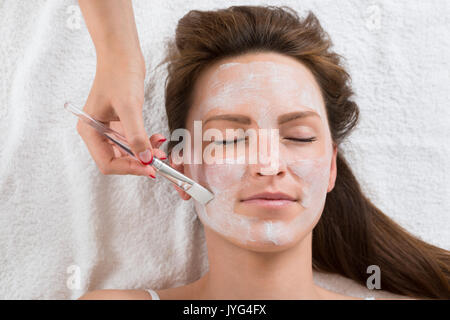 Therapeut Hände mit Pinsel auftragen Gesichtsmaske, eine junge Frau in einem Spa Stockfoto