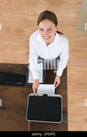 Hohe Betrachtungswinkel der Jungen Geschäftsfrau mit Drucker am Schreibtisch im Büro Stockfoto