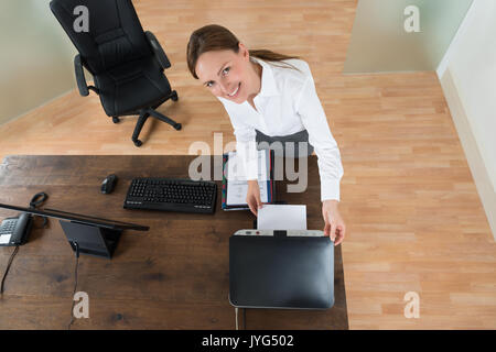 Hohe Betrachtungswinkel der Jungen Geschäftsfrau mit Drucker am Schreibtisch im Büro Stockfoto