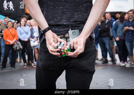 Eine Straße Magier Interpret unterhält Touristen in der Londoner Leicester Square durch Ausfüllen eines Rubik's Cube puzzle hinter seinem Rücken innerhalb von wenigen Sekunden. Stockfoto