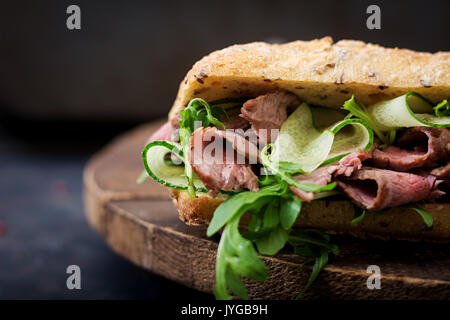 Sandwich von Vollkornbrot mit Roastbeef, Gurke und Rucola Stockfoto