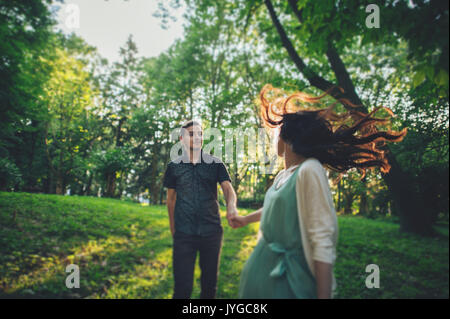 Schoß eines jungen Paares halten sich an den Händen und laufen durch den Park. Stockfoto