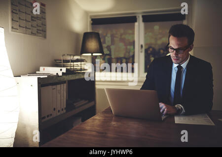 Ernst Kaufmann auf Laptop nachts sitzen im Büro suchen konzentriert arbeiten Stockfoto
