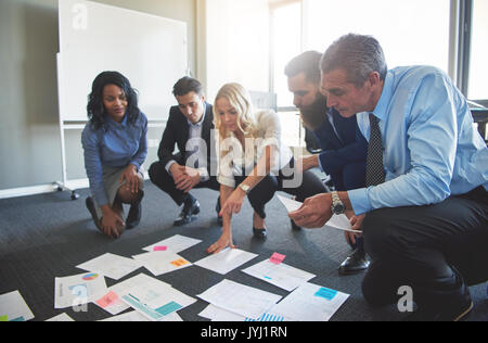 Männer und Frau Brainstorming im Büro hocken auf verschiedene Dokumente zu suchen Stockfoto