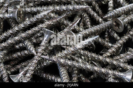 Ein Haufen von Stahl schrauben alle in einem Bündel mit Gewinde und Schlitz. Alle im Fokus auf eine kaum sichtbare schwarze Boden zurück gesetzt. Stockfoto