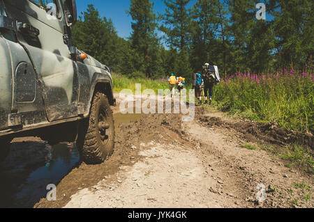 Alte russische off-road Auto ist fertig, das Hindernis in Form eines großen Schlammigen zu bewegen Pfützen auf der Straße unpassierbar. Auto ATV für schwieriges Gelände. Stockfoto