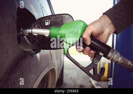 Kraftstoff auffüllen an der Tankstelle. Füllen ein schmutziges Auto an einer Tankstelle. Füllkupplung zur Betankung ein Auto in der Hand des Menschen. Stockfoto