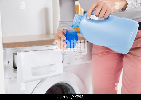 In der Nähe der weiblichen Händen Gießen Waschmittel in die Blaue flasche Cap Stockfoto