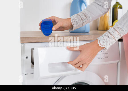 In der Nähe der weiblichen Händen gießt flüssiges Waschmittel in die Waschmaschine zu Hause Stockfoto