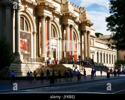 Menschenmassen versammeln sich draussen auf den Stufen des Metropolitan Museum der Kunst - Die Met-Gebäude gegenüber werfen Schatten am frühen Morgen. New York, NY, USA. Stockfoto