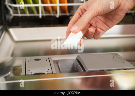 Nahaufnahme der Person Hände, Spülmaschine Seife Tablet in Spülmittel Spülmaschine Box Stockfoto