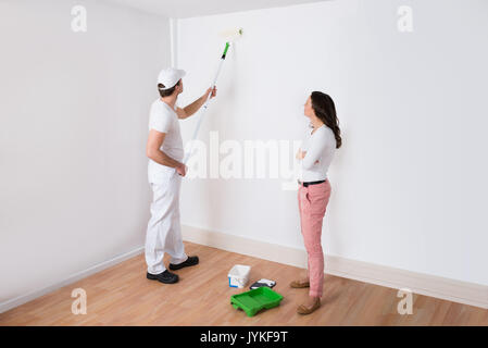 Junge Hausfrau auf Maler Malerei Wand im Haus Stockfoto
