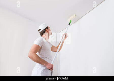 Junge Maler In weiße Uniform Malen mit Paint Roller an der Wand Stockfoto