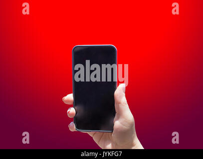 Das Telefon in der Hand auf dem roten Hintergrund Stockfoto