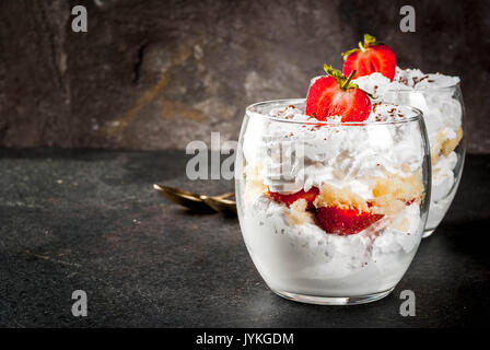 2-in-1-dessert Parfait in ein Glas mit Erdbeeren, Kuchen und Schlagsahne. Auf einem schwarzen Steintisch. Platz kopieren Stockfoto