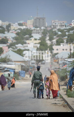 Ein Mitglied der somalischen Polizei geht eine Straße in Mogadischu mit seinem Sohn am 21. Dezember. AU UN-IST-FOTO Tobin Jones (11511062233) Stockfoto