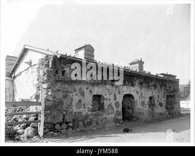 Ein Hund schläft auf dem Boden vor dem Priester' Residence der Mission San Luis Obispo de Tolosa, Ca. 1900 (CHS 4149) Stockfoto