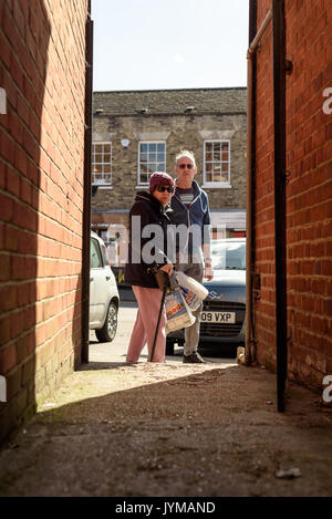Ältere Menschen peering in einer dunklen Gasse in Schatten starrte direkt in Richtung der Fotograf bei Tageslicht auf einer typischen durchschnittlichen high-Straße in E Stockfoto