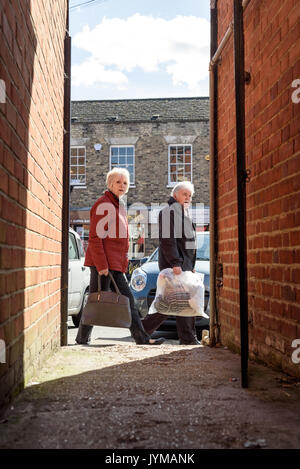 Ältere Menschen peering in einer dunklen Gasse in Schatten starrte direkt in Richtung der Fotograf bei Tageslicht auf einer typischen durchschnittlichen high-Straße in E Stockfoto