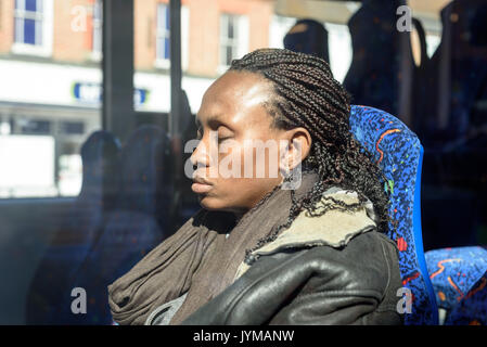 Sleepy schwarze Frau mit Rastalocken Haare sitzen auf einem Bus im hellen Sonnenschein Stockfoto