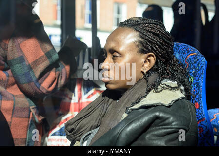 Sleepy schwarze Frau mit Rastalocken Haare sitzen auf einem Bus im hellen Sonnenschein Stockfoto