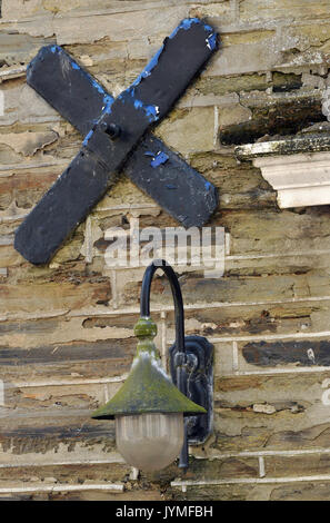 Eine alte Mauer aus Stein mit einer gusseisernen Wand Krawatte und ein Licht in Moos bedeckt. Stockfoto