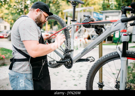 Fahrradmechaniker Reparatur der vorderen Gangschaltstange. Zyklus Workshop Outdoor. Fahrrad Befestigung auf Halterung Stockfoto