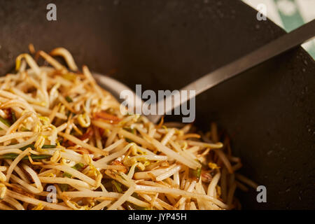 Gebratene Sojabohnensprossen und Frühlingszwiebeln in einem schwarzen Stahl wok Rühren Stockfoto