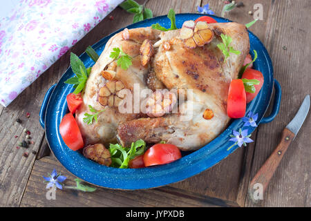 Zwei gebratene Hähnchenschenkel mit in Scheiben geschnittenen Tomaten Stockfoto