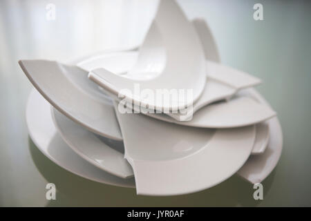 Stapel gebrochen weiße Platten auf Glas Tisch Stockfoto