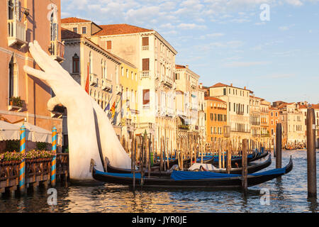 Lorenzo Quinn unterstützen mit den Händen unterstützen Ca'Sagredo Hotel und den Grand Canal bei Sonnenuntergang, Venedig, Venetien, Italien mit angelegten Gondeln in Th Stockfoto