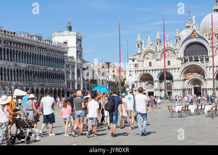 Tour Gruppe mit Familien und Kinder in der Piazza San Marco, Venedig, Italien nach ihrem Tour Guide mit dem blauen Schirm wandern in Richtung des Bas Stockfoto