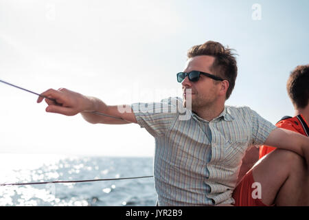 Junge kaukasier Sailor gerne entspannen auf Segelboot Yacht. Er loooks beiseite und Traum. Stockfoto