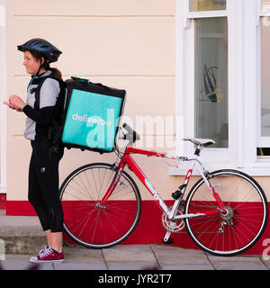 Der Gig Wirtschaft in Großbritannien: Eine junge-Frau Mädchen beschäftigt mit ihrem Fahrrad für Deliveroo, die Speisen zum Mitnehmen Lieferservice Stockfoto