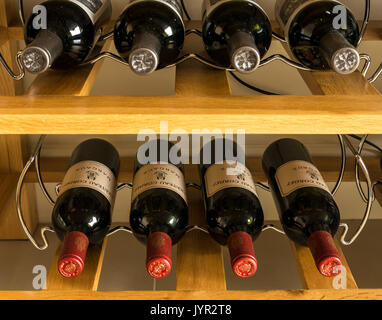 Rotwein Flaschen aus der Region Bordeaux in Frankreich, einschließlich Margaux, Modalitäten in einem Metall Weinregal in Eiche Kommode Stockfoto