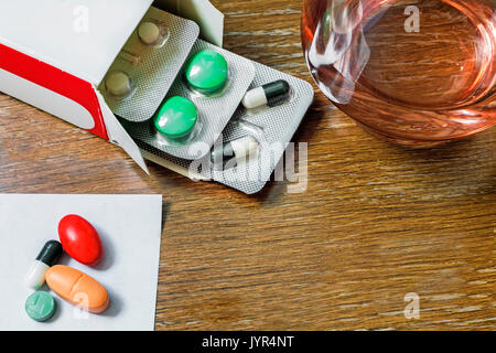 Auf dem Tisch liegen verschiedene Arten von Pillen und Fläschchen. Neben einem Glas Wasser steht für die Verwendung der Medikamente. Stockfoto