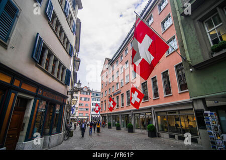 Downtown City Szene von schmalen Einkaufsstraße mit vielen Schweizer Fahnen aus Zürich Schweiz Stockfoto