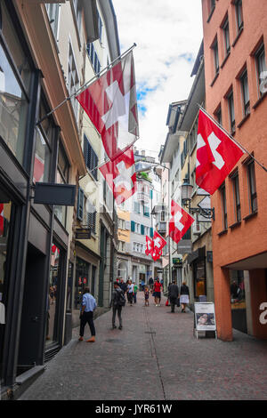 Downtown City Szene von schmalen Einkaufsstraße mit vielen Schweizer Fahnen aus Zürich Schweiz Stockfoto