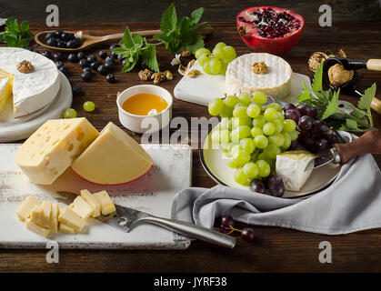 Käse mit Trauben, Honig und Nüssen auf dunklen Holztisch. Stockfoto