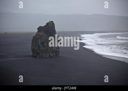 Felsformation auf schwarzen vulkanischen Strand am Kap Dyrhólaey im Süden Islands in nebliges Wetter Stockfoto