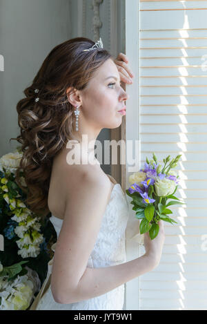 Junge attraktive Braut auf Brautkleid im Studio Stockfoto