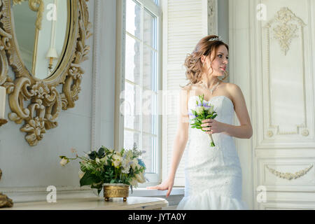 Junge attraktive Braut auf Brautkleid im Studio Stockfoto