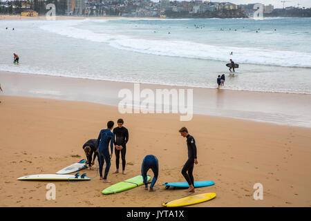 Junge Männer Surfer mit Surfbrettern auf Manly Beach im Winter, Sydney, Australien Stockfoto