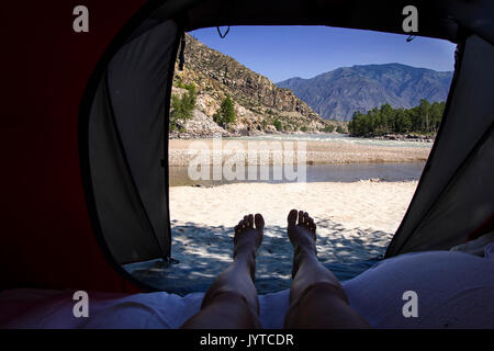 Blick von touristische Zelt innen auf dem Berg Landschaft mit Fluss. womans Beine in die Berge Stockfoto